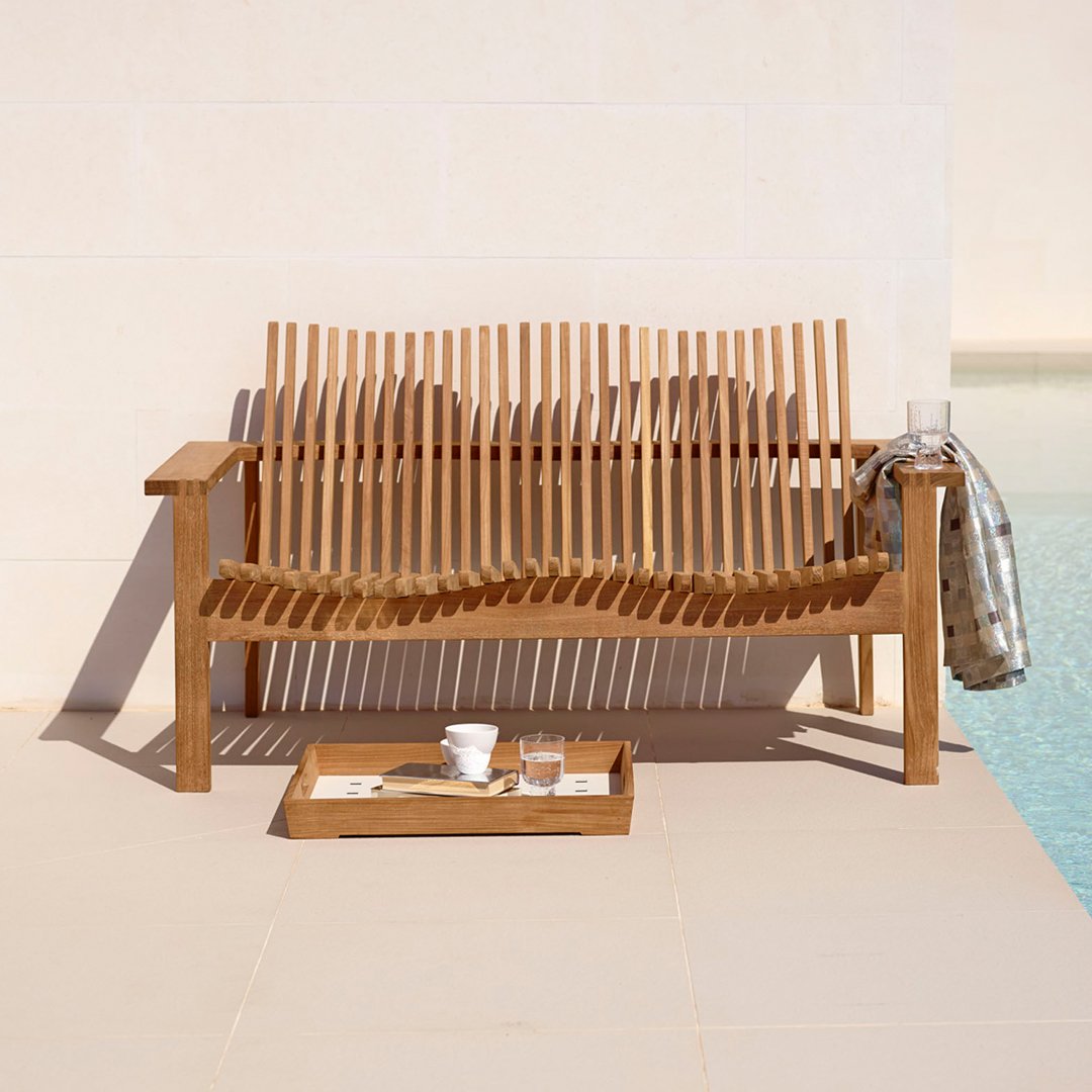 Natural wood bench with a slatted design, featuring warm tones and a simple, modern pattern against a light backdrop.