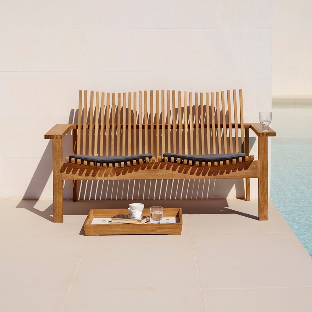 Natural wood tones with sleek black cushions; modern slatted design enhances outdoor elegance.