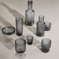 Set of sleek grey glassware featuring various shapes and textured patterns. Modern, sophisticated table decor.