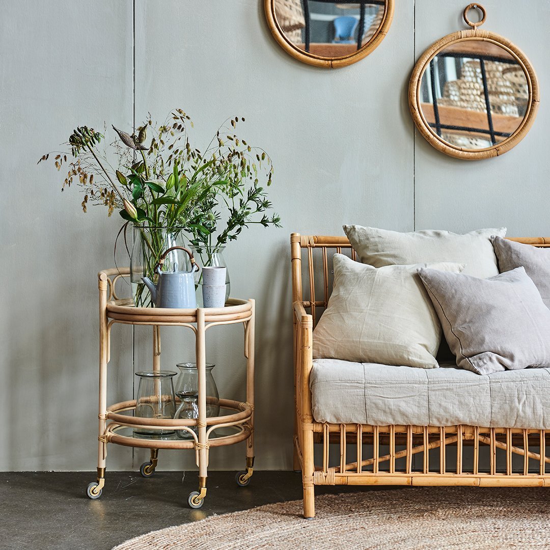 Rattan side table with natural beige tones, showcasing a minimalist design and soft-textured cushions in neutral colors.