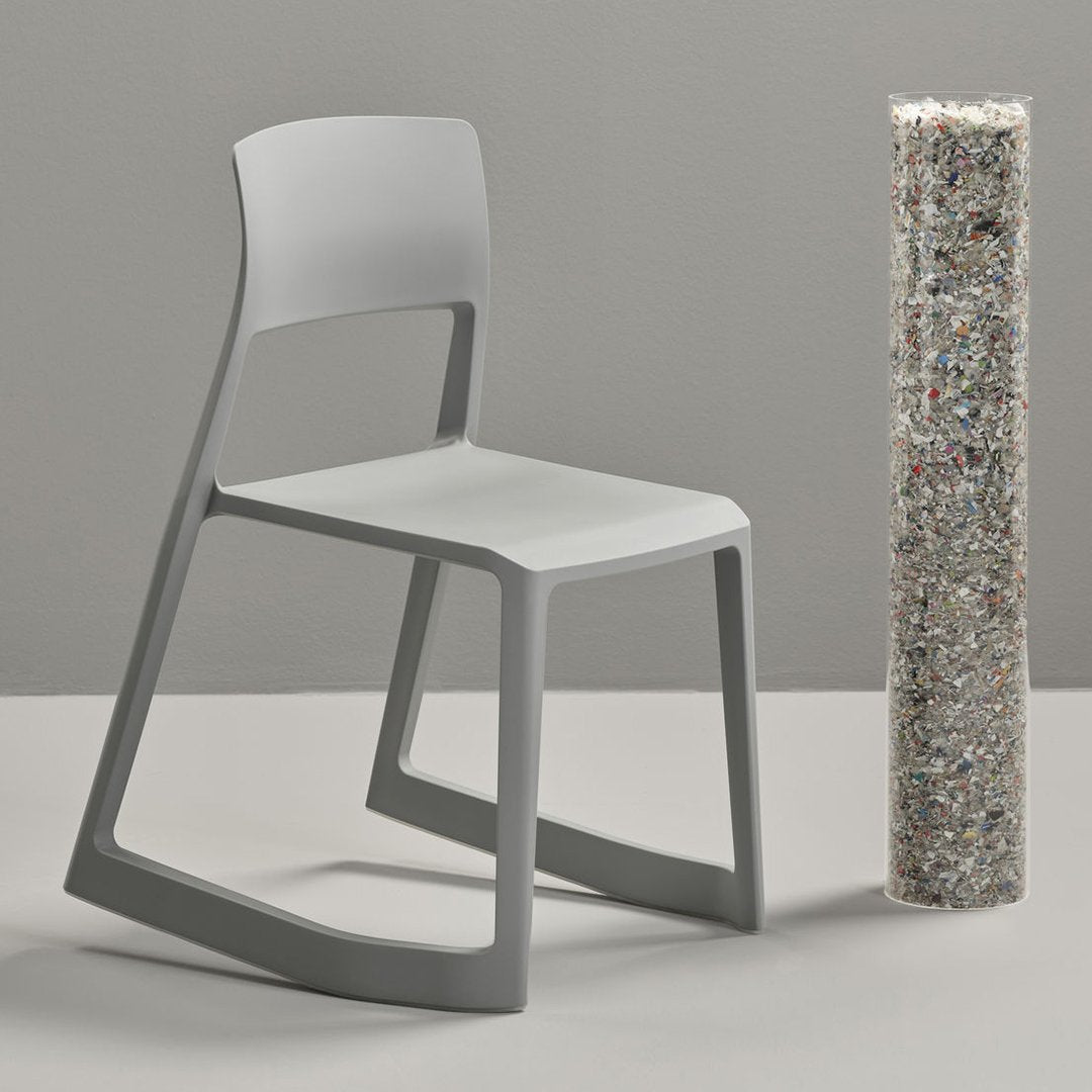 Modern gray chair with a sleek design, paired with a textured, colorful, recycled material column on a neutral backdrop.