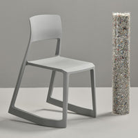 Modern gray chair with a sleek design, paired with a textured, colorful, recycled material column on a neutral backdrop.