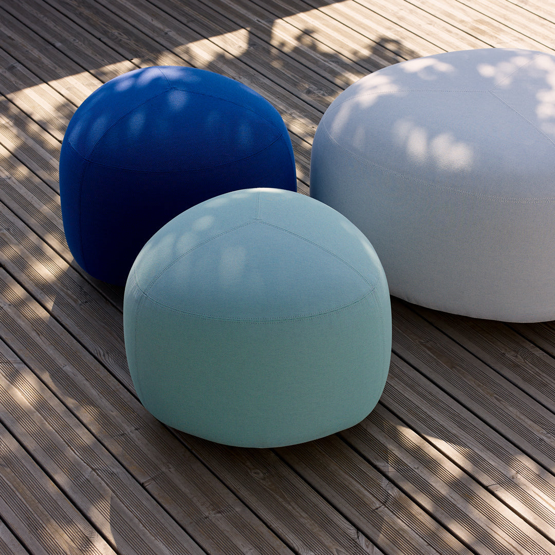 Three round poufs in dark blue, light blue, and white on wooden decking, showcasing vibrant colors and smooth textures.
