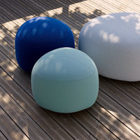 Three round poufs in dark blue, light blue, and white on wooden decking, showcasing vibrant colors and smooth textures.