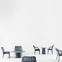 Set of elegant dark blue chairs with perforated patterns around a minimalist blue table on a white background.