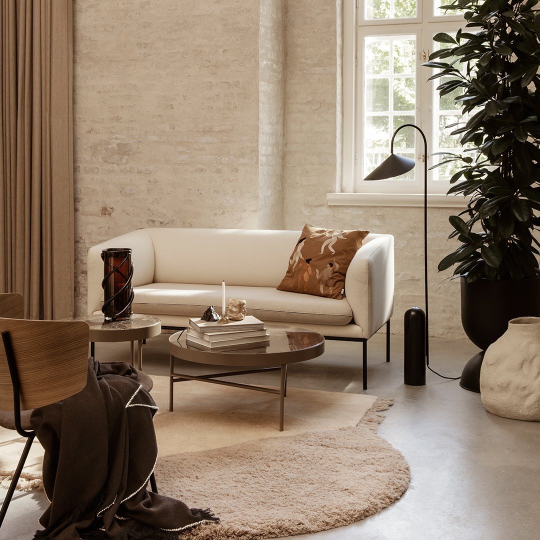 Modern white sofa with a patterned brown cushion, earthy tones, and soft textures in a stylish, minimalistic living space.