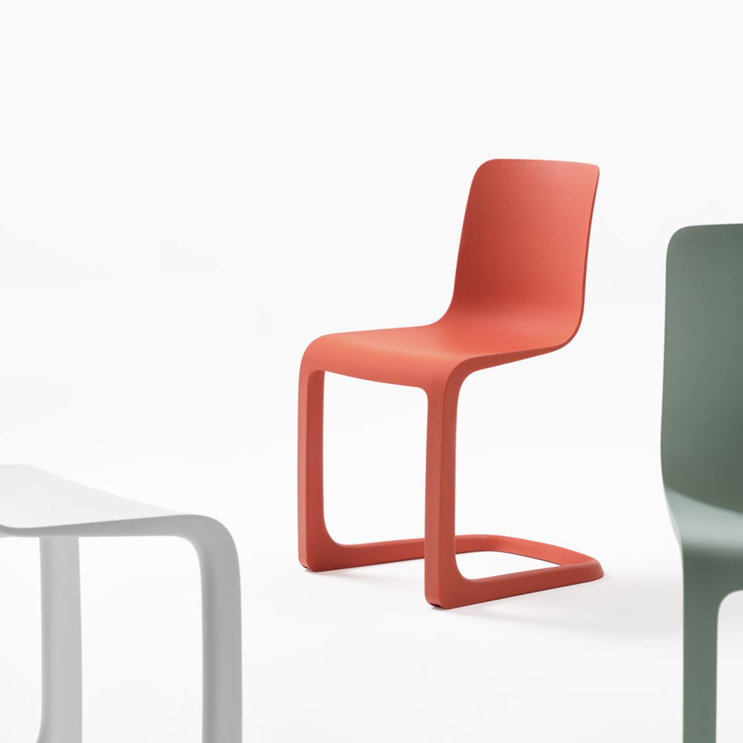 Colorful modern chairs in coral, green, and white featuring smooth, minimalist designs and sleek lines.