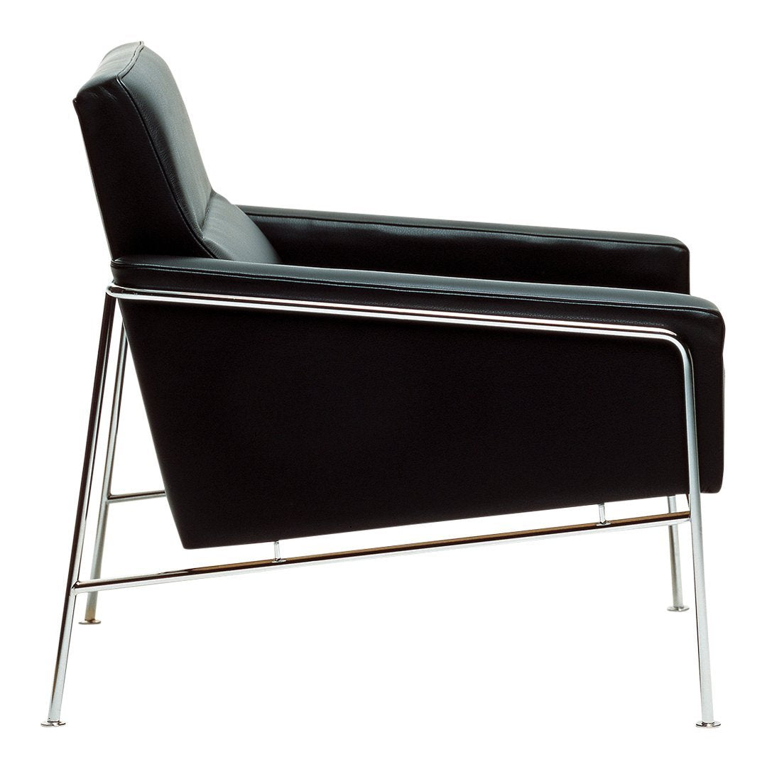 Black leather armchair with sleek chrome legs, featuring a minimalist design and smooth, modern lines.
