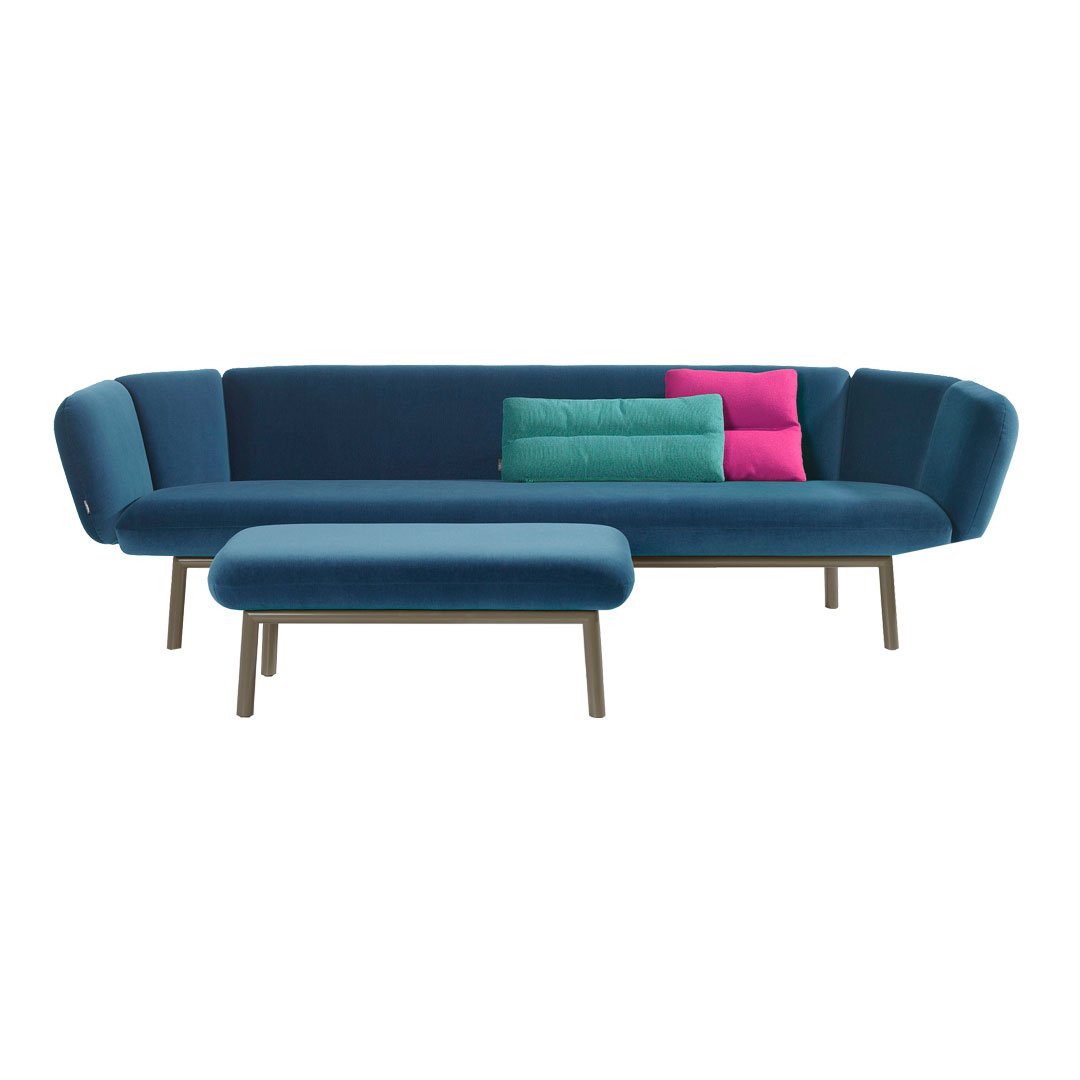 Modern blue sofa with curved design, featuring vibrant pink and teal accent pillows on a wooden base.