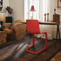 Bold red chair on a textured brown rug, set in a stylish workspace with natural light and unique decor elements.