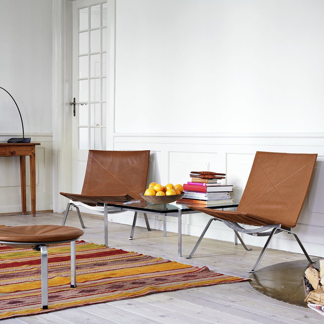 Brown leather chairs paired with a colorful striped rug featuring reds, yellows, and oranges.