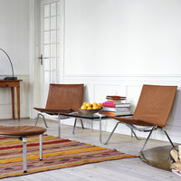 Brown leather chairs paired with a colorful striped rug featuring reds, yellows, and oranges.