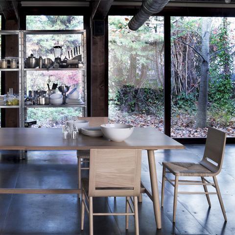 Light wood dining set with sleek lines, featuring a minimalist design against a backdrop of greenery and natural light.