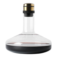 Elegant clear glass decanter with a black base and gold accent on the stopper, showcasing deep red wine.