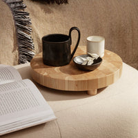 "Round wooden tray with a natural bamboo finish, featuring a black cup and white candle against a soft, neutral background."