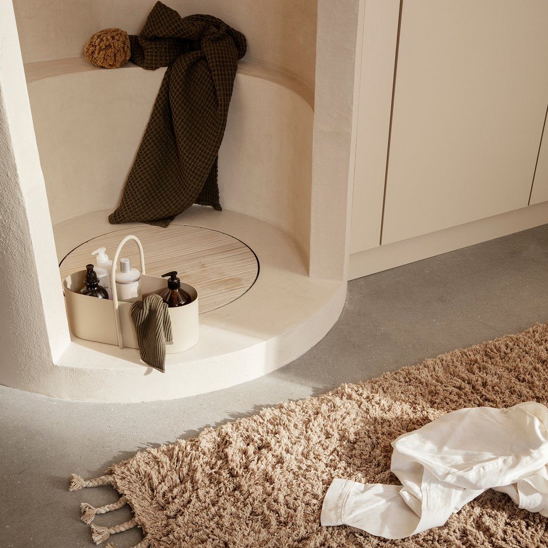 Neutral beige tones with earthy green and soft white accents, featuring a textured brown rug and clean lines.