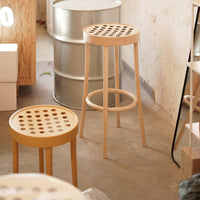 Light wooden bar stools with circular cutout patterns, featuring a natural finish in a cozy interior setting.
