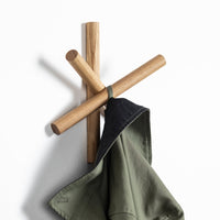 Wooden coat hook in natural finish with olive green and navy blue garment, modern minimalist design.