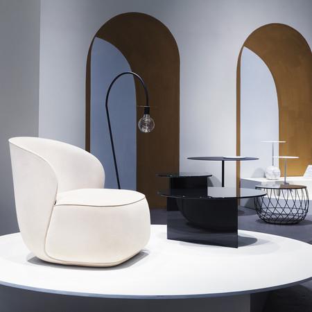 White curvy chair on a round table with black and white geometric patterns in a modern, minimalist setting.