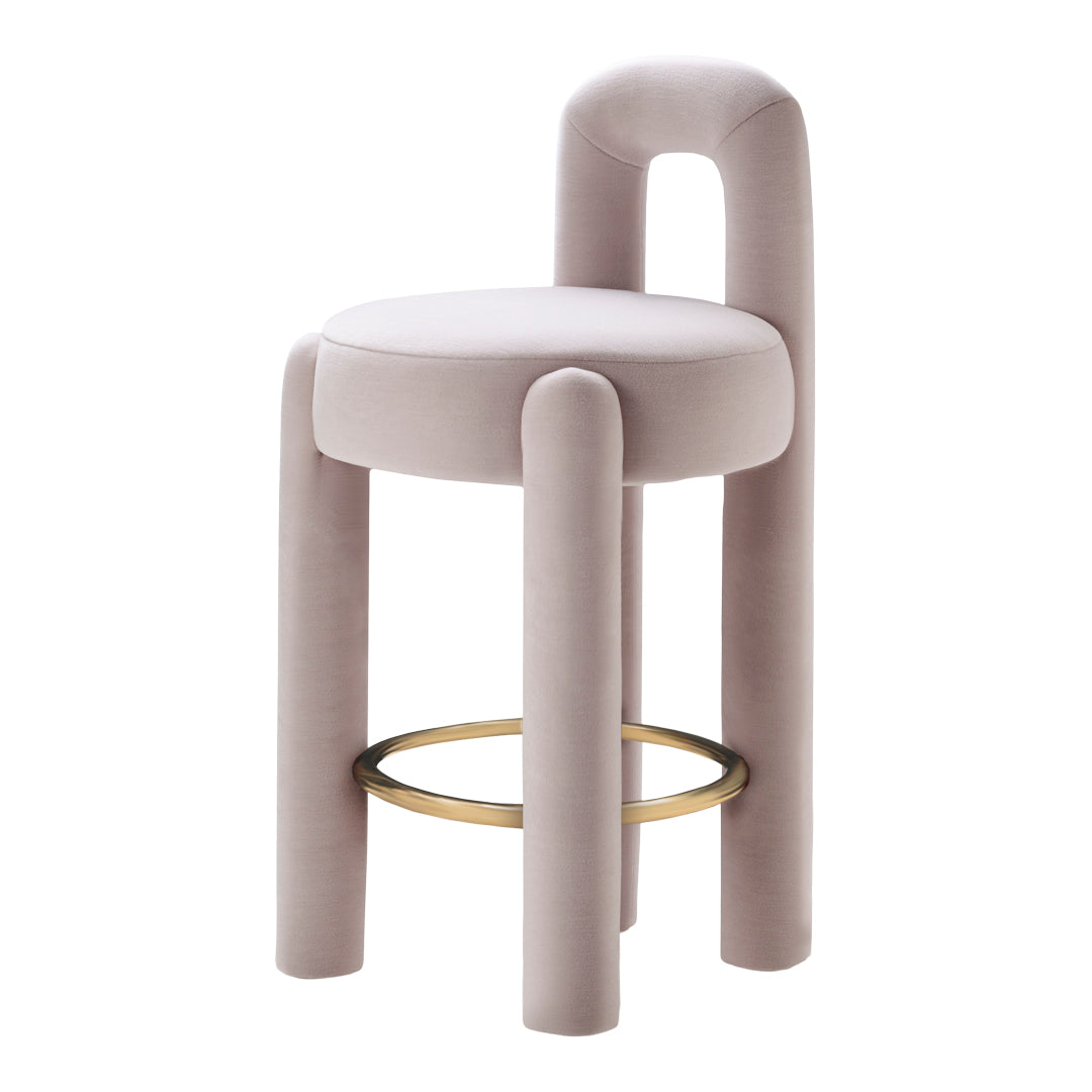 Pastel pink velvet stool with rounded edges and a gold circular footrest, showcasing minimalist design and soft textures.