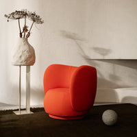 Vibrant orange swivel chair with smooth curves, against a neutral background and dark-textured floor.