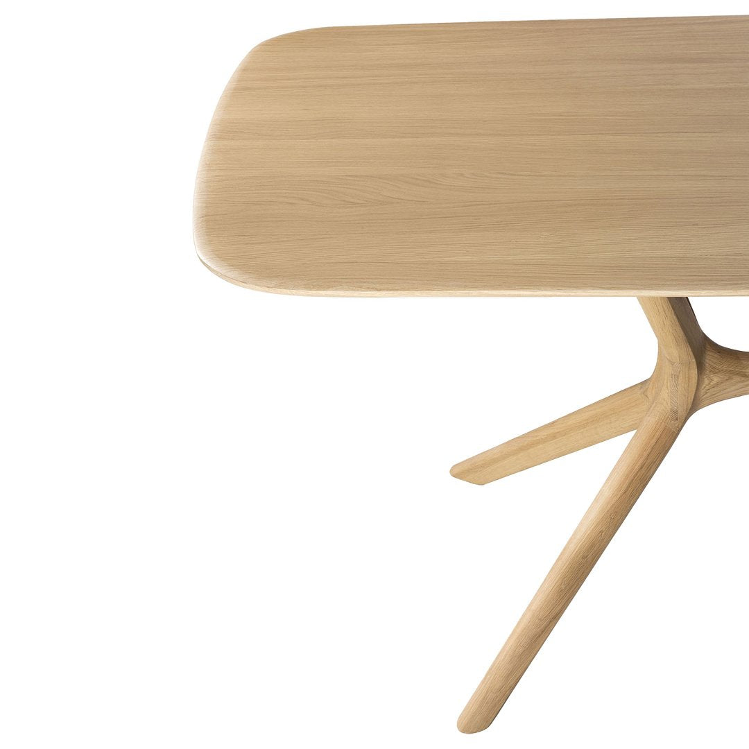 Natural oak wood table with a smooth, rounded top and minimalist design, showcasing warm beige tones and subtle grain patterns.