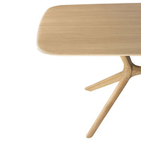 Natural oak wood table with a smooth, rounded top and minimalist design, showcasing warm beige tones and subtle grain patterns.