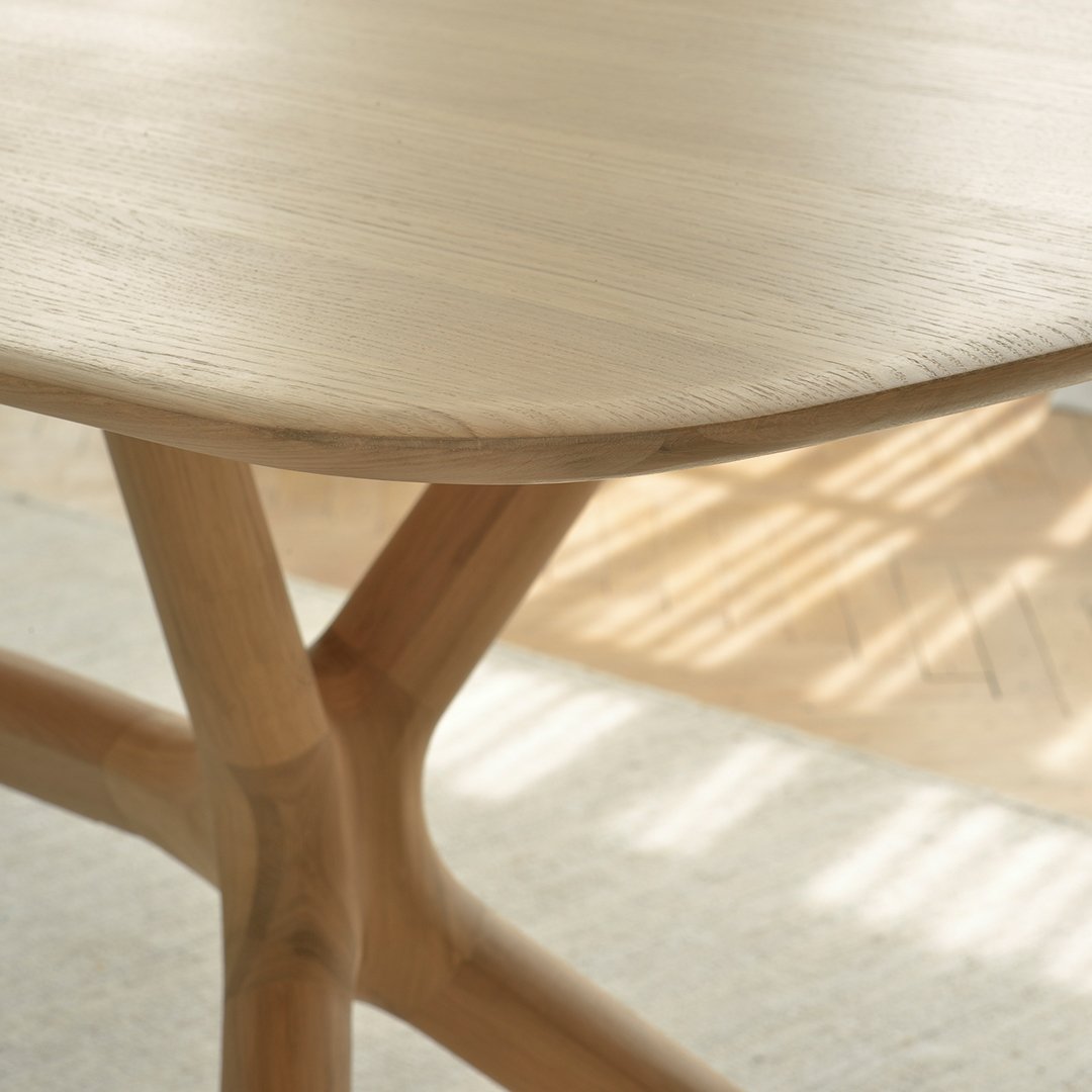 Natural wood table with a smooth, curved surface and light beige hues, showcasing subtle grain patterns and elegant design.