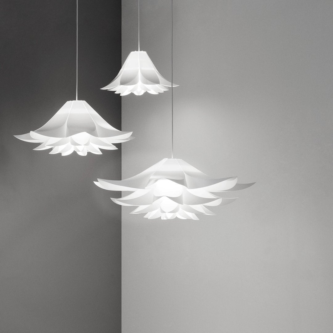 Three white pendant lamps with layered floral patterns, hanging against a soft gray wall.