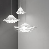 Three white pendant lamps with layered floral patterns, hanging against a soft gray wall.