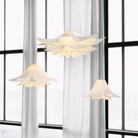 "Elegant white floral pendant lights with layered petal design, set against sheer white curtains and bright windows."