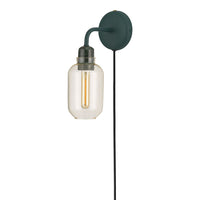 Green wall-mounted lamp with a clear glass shade and gold filament bulb, featuring a sleek, modern design.