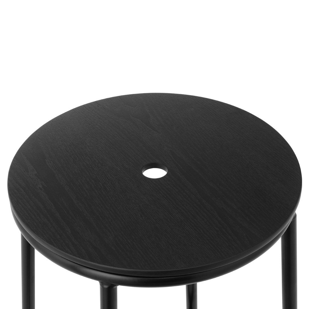 Black round stool top with a smooth finish and a center hole, complemented by slender black legs.