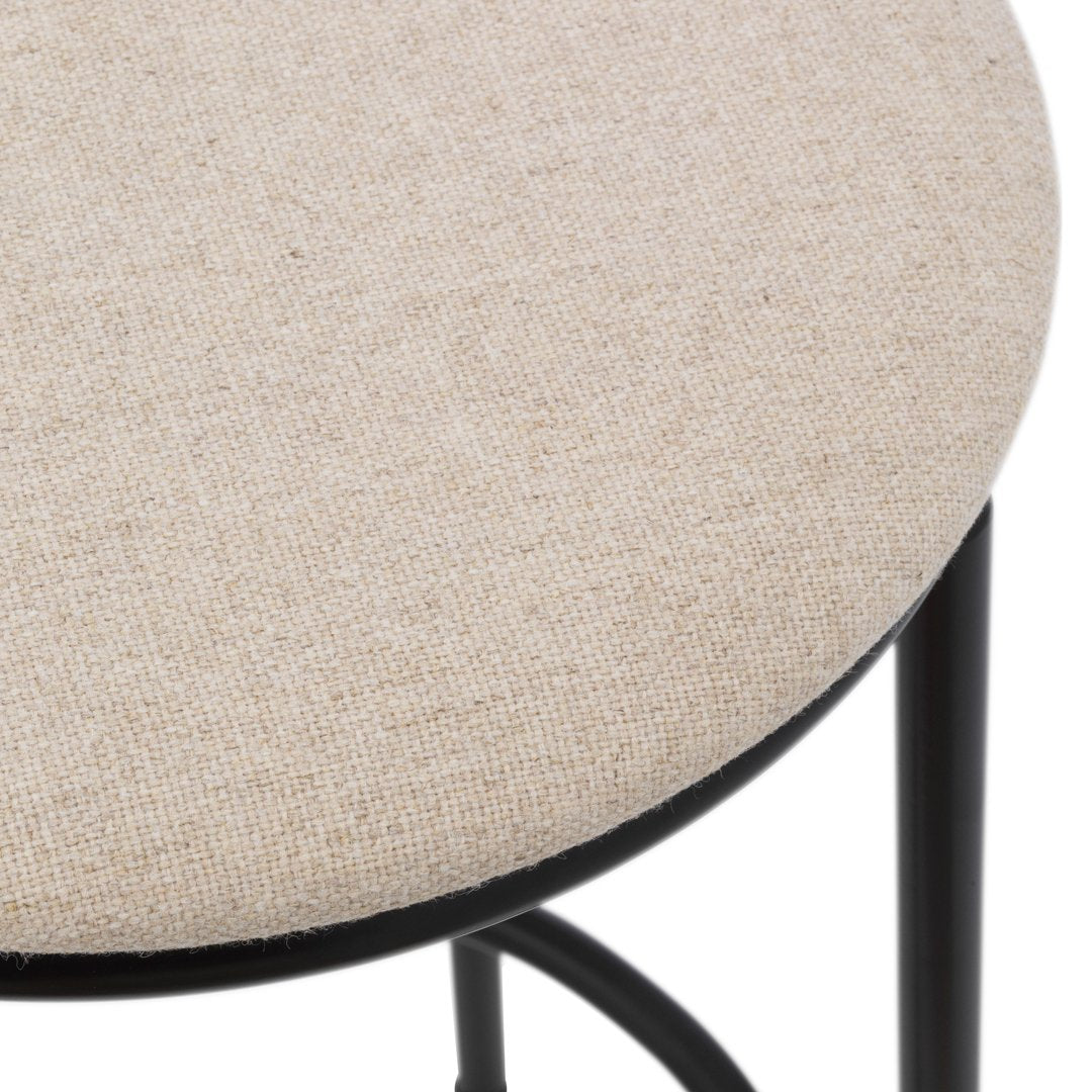 Beige linen stool top with subtle texture, paired with a sleek black metal frame.
