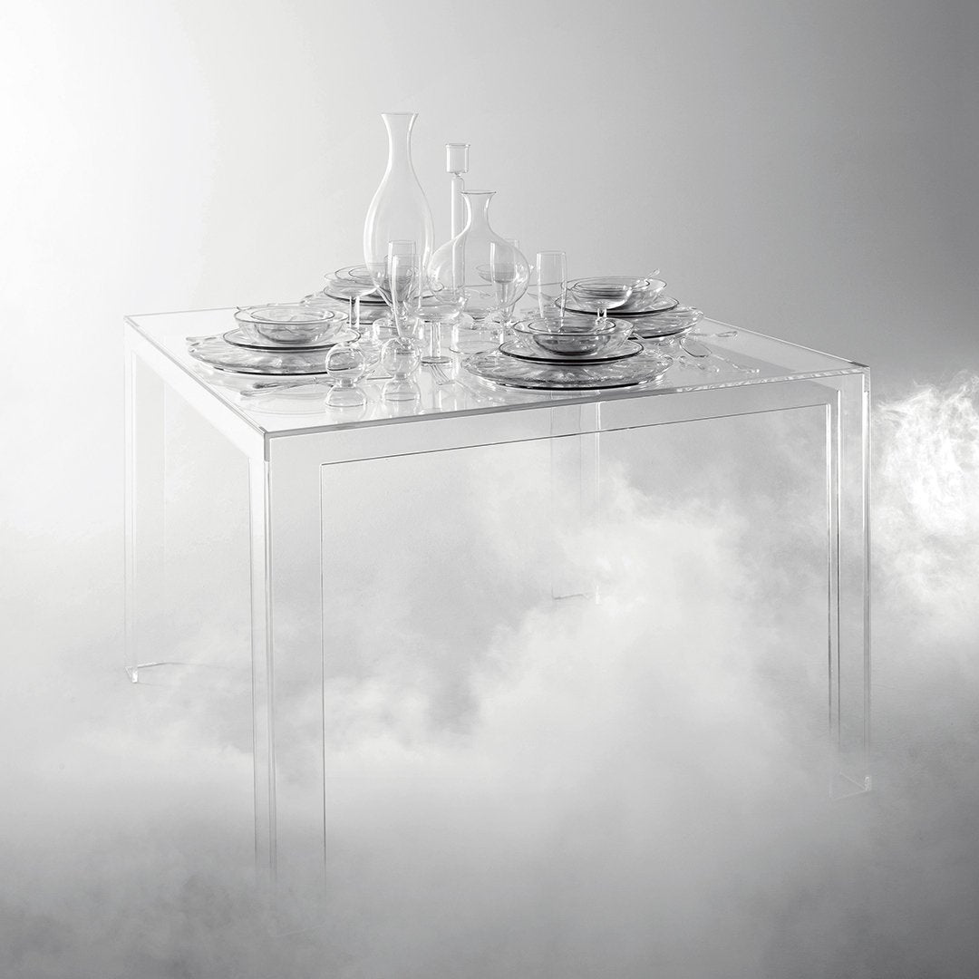 Clear acrylic table with elegant glassware and fine china, set against a soft, white foggy background.