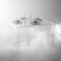 Clear acrylic table with elegant glassware and fine china, set against a soft, white foggy background.