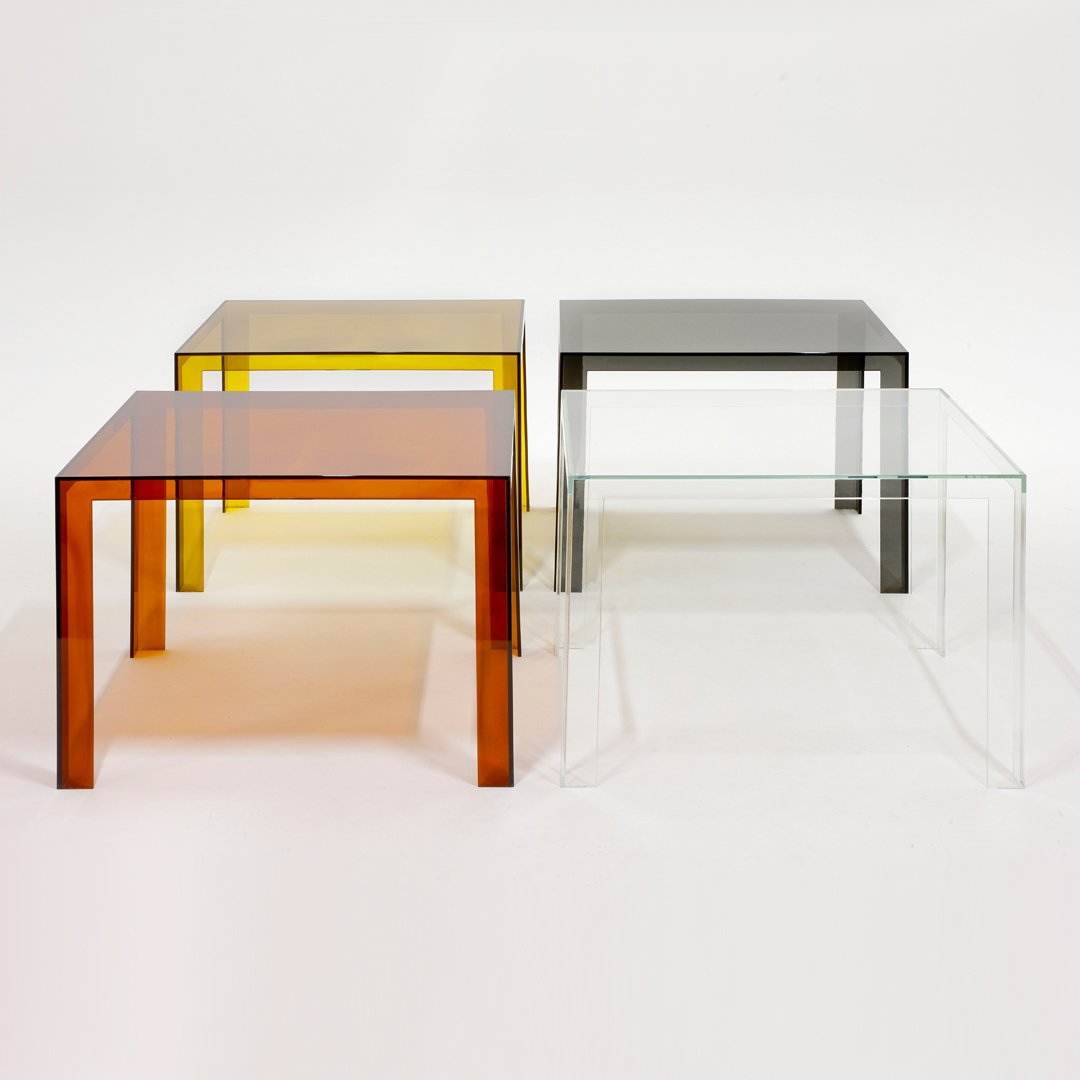 Set of four modern side tables in amber, yellow, black, and clear glass, featuring a minimalist design.