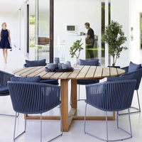 Navy blue patio chairs with sleek lines around a rustic wooden table in a modern indoor space.
