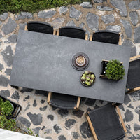 Rectangular gray tabletop with subtle texture, surrounded by black chairs on a stone-patterned patio.