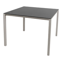 Square dining table with a sleek black top and minimalist silver legs, offering a modern, stylish design.