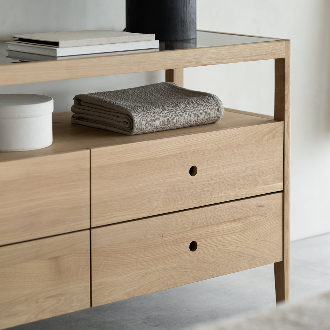 Light oak sideboard with minimalistic design, featuring a smooth finish and simple, neutral-colored textiles.