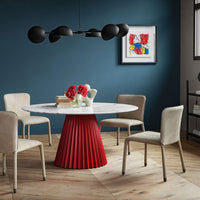 Stylish white marble table with red pleated base, beige chairs, black pendant lights, and vibrant wall art.