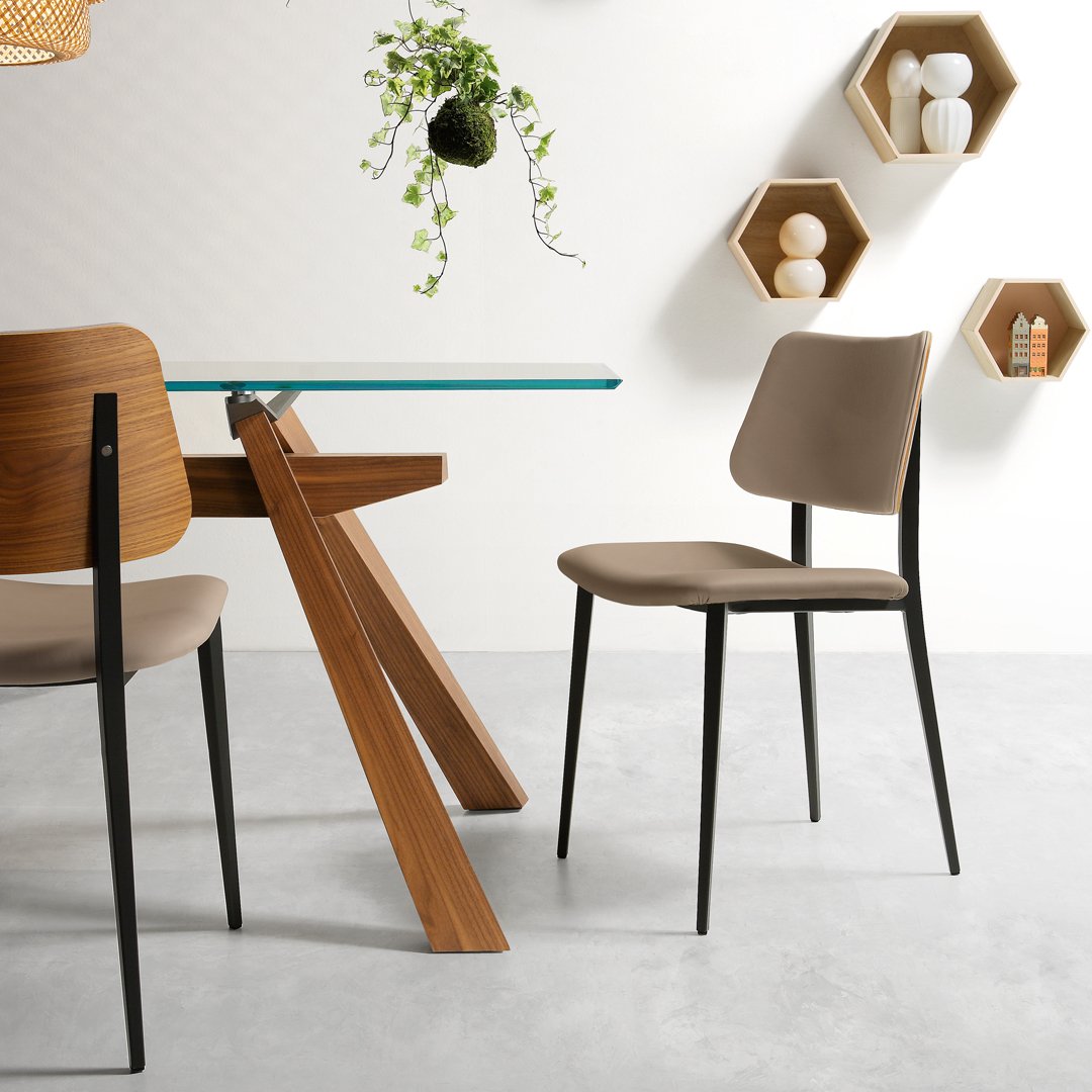Beige modern dining chair with a sleek black frame, paired with a wooden table and light gray concrete flooring.
