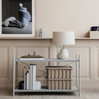Stylish gray shelf with beige decor and soft patterns, featuring a textured white lamp and natural woven baskets.