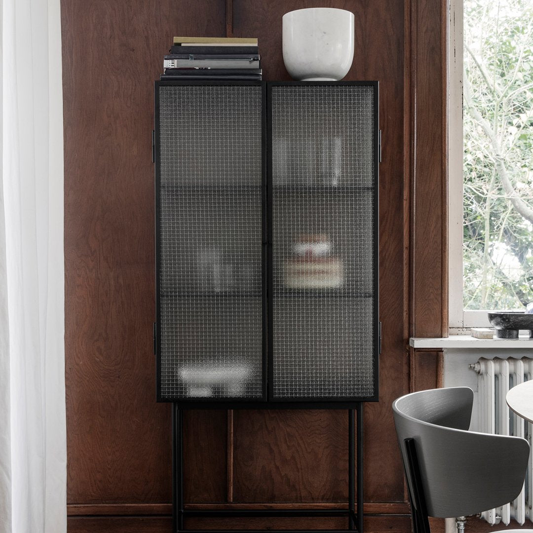 Modern black cabinet with a grid pattern, featuring sleek lines and a minimalist design against a wood backdrop.