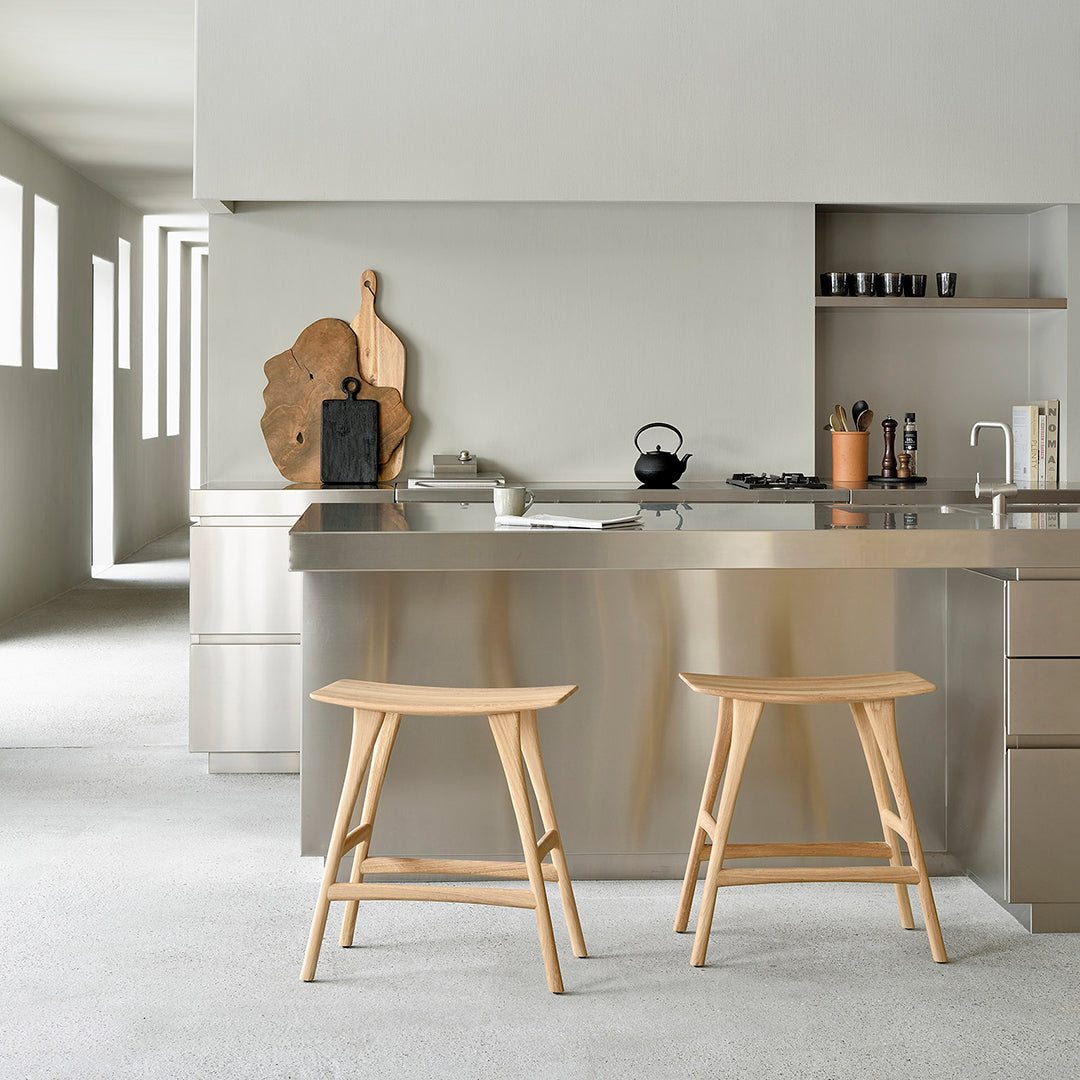 Light wood bar stools set against a sleek gray kitchen backdrop, featuring minimalist design and modern aesthetics.