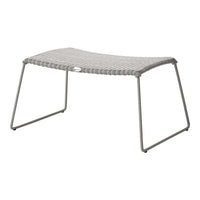 Gray woven outdoor stool with a sleek, modern design and sturdy metal legs. Ideal for patio or garden decor.