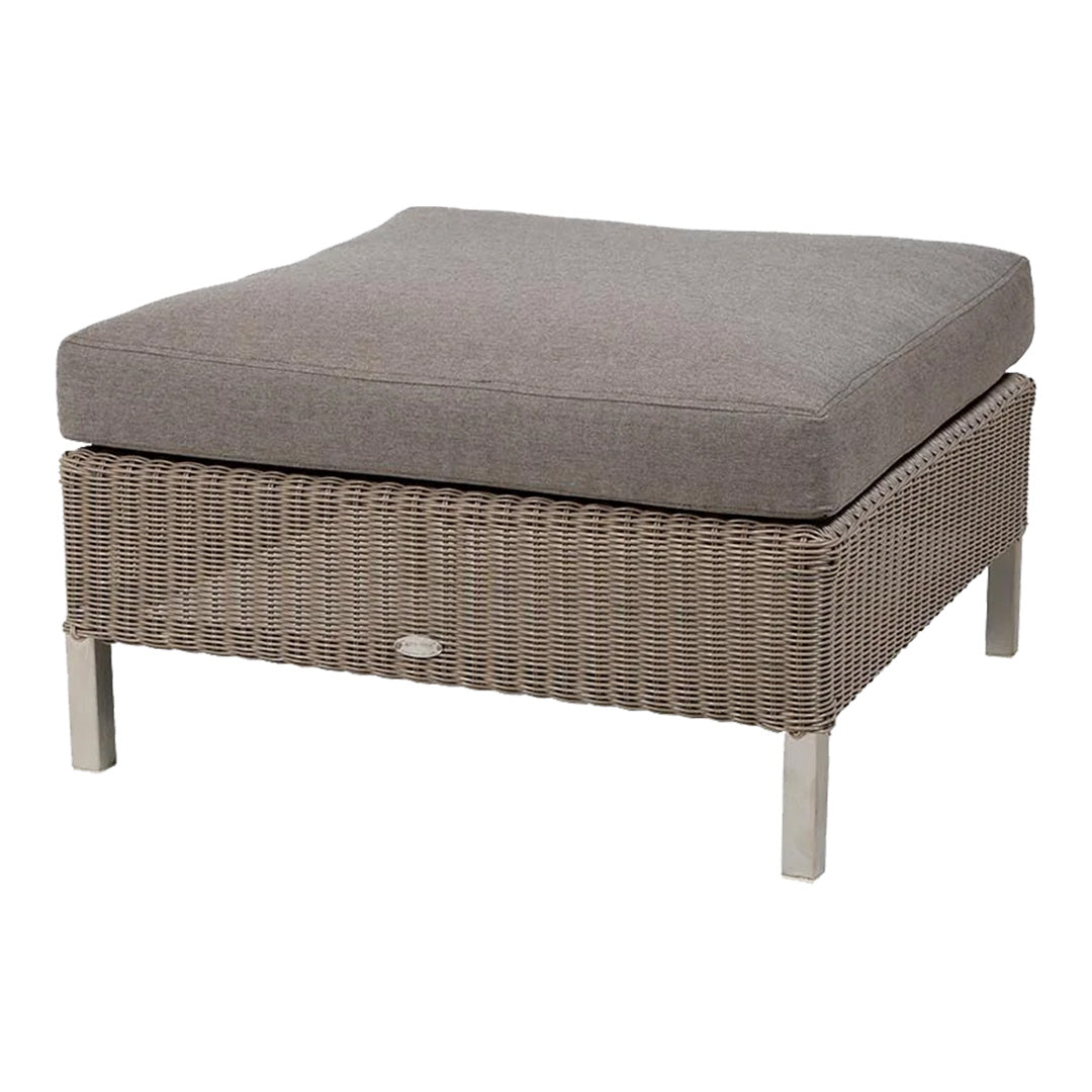 Gray cushion on a woven wicker ottoman with silver legs, featuring a modern, textured pattern.