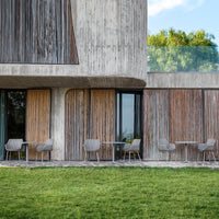 Modern building with neutral gray concrete and warm wooden accents, featuring a grassy courtyard.