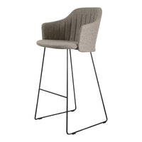 Gray upholstered bar stool with vertical ribbed pattern and sleek black metal legs. Stylish and modern design.